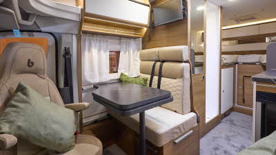 The Benimar Tessoro T861 has a grey carpet, with white cabinets.  The upholstery is cream and light  brown.  There is a fixed rear bed.  There are two green cushions.