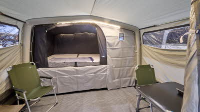 Campmaster AIR 1000 LX interior, cream canvas, the sleeping area is unzipped.  There are two lime green canvas chairs.