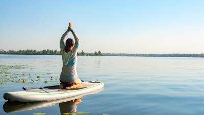 woman doing yoga on a paddleboard on calm blue waters