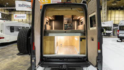 The Mega Mobil Mega Re-Aktiv 680S 4X4 has a rear bed with a storage underneath which is lit.  Both its rear doors are open and there is a spare wheel on the left hand door.