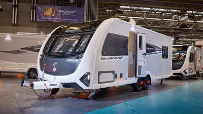 Swift Conqueror Grande 650L is white with black decals and a black front panel.  Its corner steadies are down and its entrance door is open.