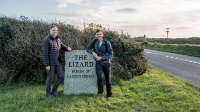 Two men leaning on a stone reading - The Lizard, parish of Landewednack