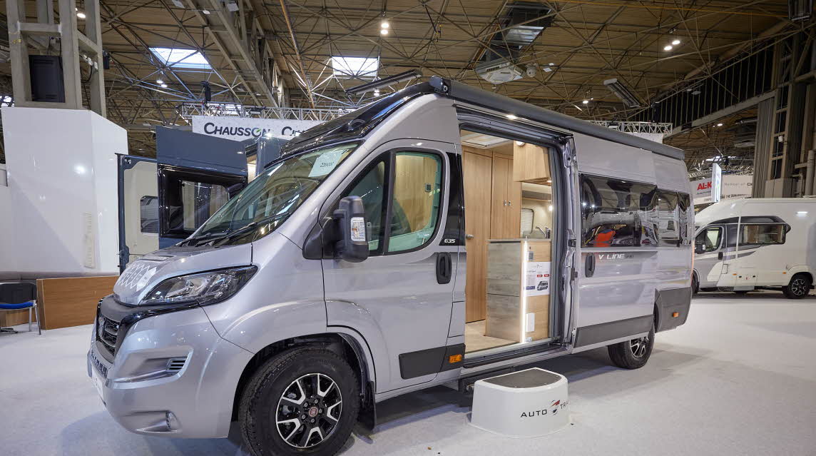 Auto-Trail V-Line 635 Sport has a silver exterior.  The sliding door is open showing the interior, with a  step to gain easy access.