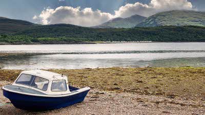Boat sitting on the sand by Loch Linnhe lake