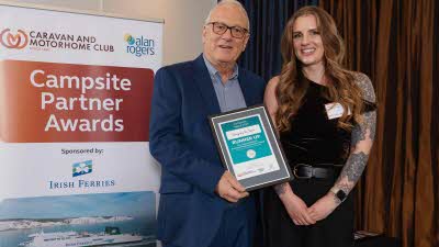 A Caravan and Motorhome Overseas Campsites Award Runner Up with the Chairman next to a sign showing Campsite Partner Awards, with Irish Ferries below it