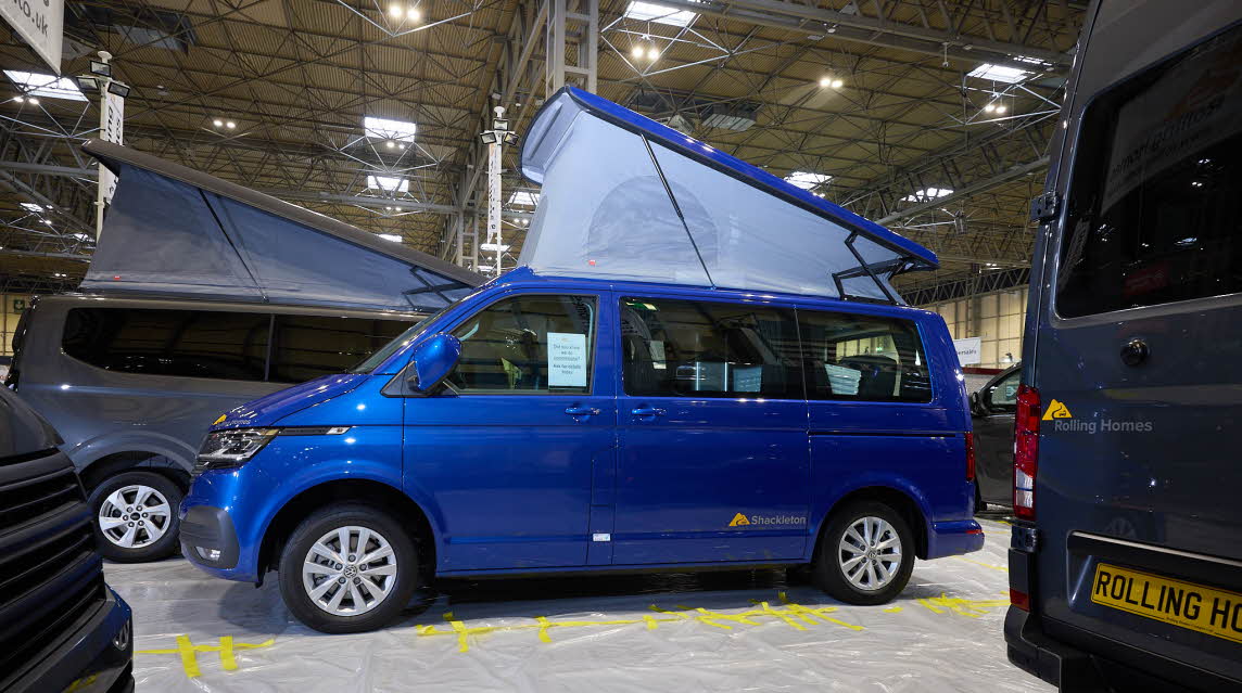 The Rolling Homes Camper Ltd Shackleton has a bright blue exterior.  Its rising roof is fully extended.
