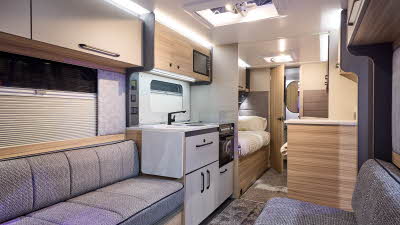 Interior of the Bailey Phoenix Black 642 with grey sofas and wood accents, large windows and two skylights will let natural light flood in.  To the rear the washroom door is open.  