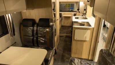 The Elddis Autoquest APEX 196+ has brown upholstery with complementary furniture in paler wood.  At the rear there is a second lounge.