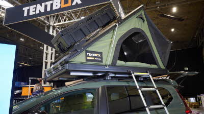 TentBox Cargo 2.0 is shown on a Dacia. The canvas is green and it has a black hard top with a storage box. There is a silver ladder to gain access.