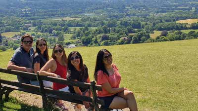 Five people sitting on a bench overlooking the Surrey Hills