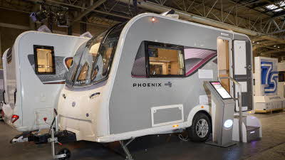 Bailey Phoenix GT75 420 exterior which has pale grey sides with an all white front.  The door is open and there are steps to gain easy access to the interior.  The skylight is open and there is an interactive pedestal next to the steps