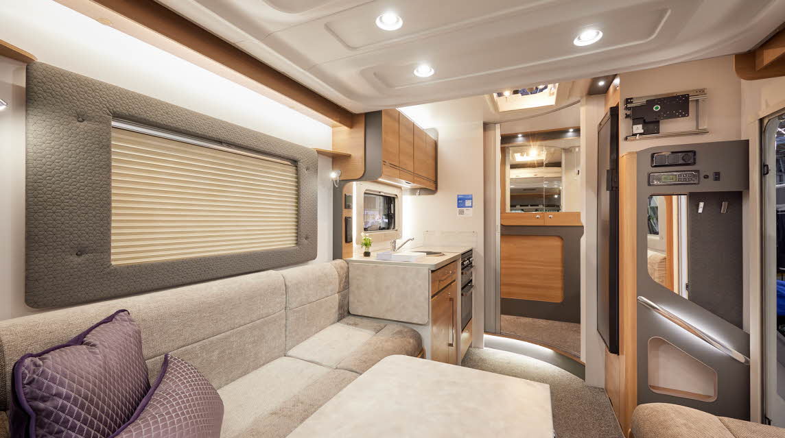 Bailey Adamo 69-4 has beige upholstery, with wooden overhead lockers.   The kitchen has a round sink and a flap to extend kitchen work surface.  The vehicle has a rear washroom