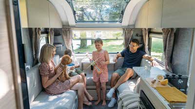 Inside an Adria Altea caravan with a smiling family sitting with a dog