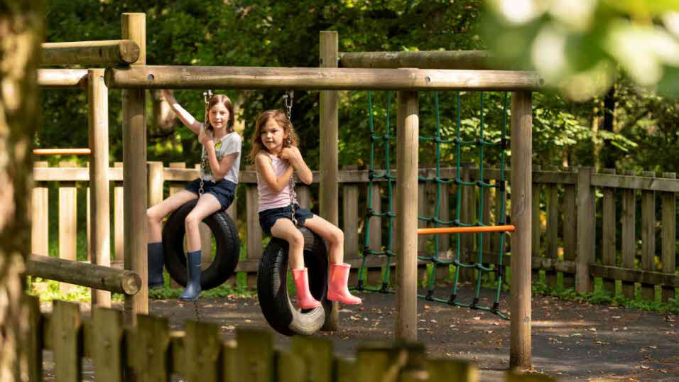 Children playing on tyre swings in Coniston Park Coppice