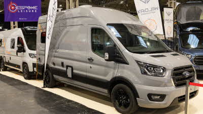 The WildAx Motorhomes Meteor is silver with black and orange decals.  There is a feather flag to its rear.