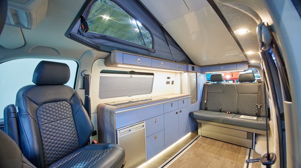 Campervan interior, blue kitchen, rising roof, grey fridge, leather driver's seat