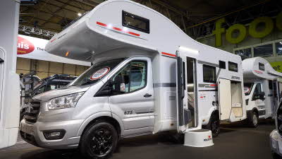 The Roller Team Zefiro 675 has a silver cab and its body is white with grey and red decals. There is a white step outside the open habitation door. The rear locker door is open.