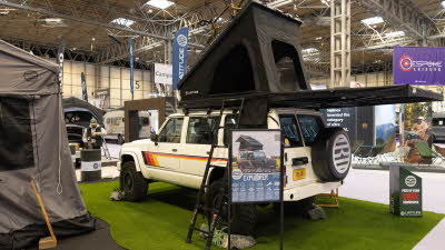 The Latitude Tents Explorer has black canvas and has platform.  There is a black ladder to gain access.  It is displayed on a white 4x4 vehicle.