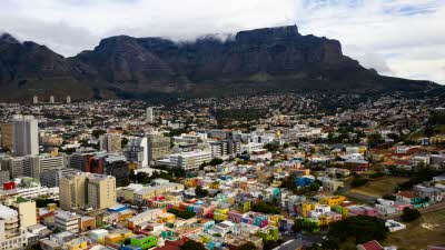 View from above of the brightly coloured buildings with the night mountains behind with the tops hidden in the clouds Cape Town, South Africa