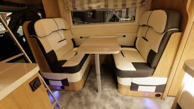 The Roller Team Auto-Roller 746 has cream and brown upholstery.  The sofas are positioned around a table.  To the left there is a ladder for access to the roof bed.