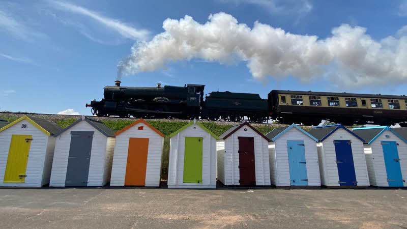 Steam train passing beach huts at Goodrington Sands