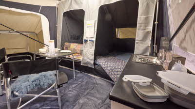 In the Camp-Let North there is a dining table and chairs. Both bedroom doors are open. The kitchen area is at the front.