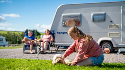 Girl playing with dog outside her caravan