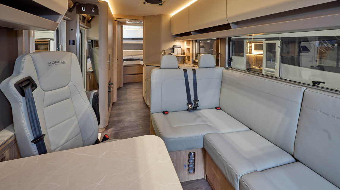 The MORELO LOFT PREMIUM 86LB has wooden flooring with cream cabinets.  The upholstery is cream leather.  There is a cream table in front of the sofas.  There are fixed rear beds at the rear.  