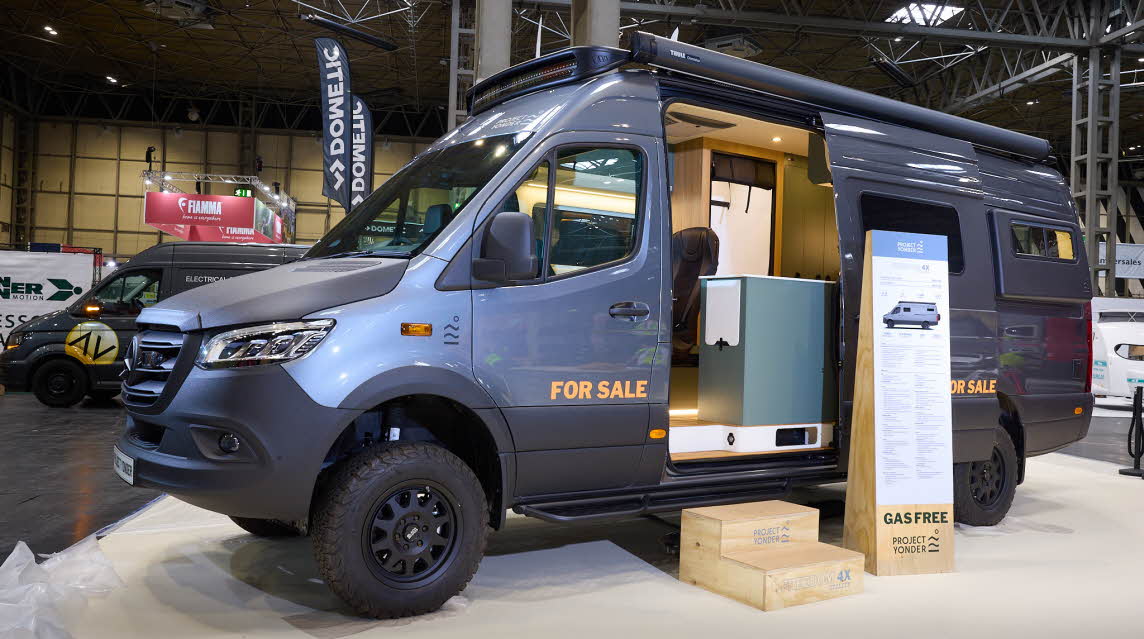 Project Yonder Freedom 4X Utility has a metallic blue exterior with black trim.  There are two steps leading to the open habitation door which reveals the interior.