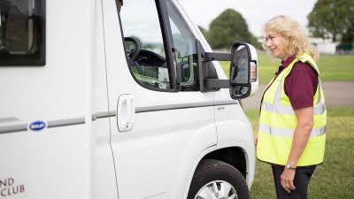 Woman in hi-vis jacket talking to a motorhome driver