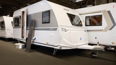 Knaus Sport 450 FU's exterior is white with a grey decal along the sides.  The door is open and there is a step to gain easy access to its interior.