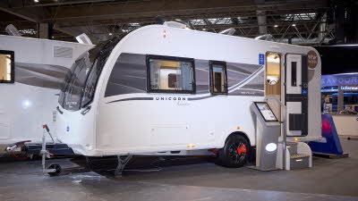 Bailey Unicorn Deluxe Seville’s exterior is white with a grey and yellow patterned decal from the front to the rear.  The entrance door is open and there are two metal steps to gain easy access.  There is an interactive display board to the left