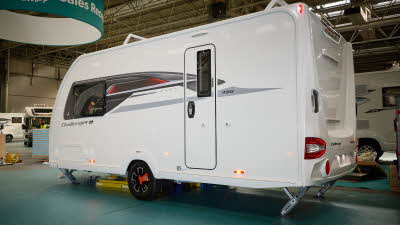 Swift Challenger Grande SE 480's exterior is white with grey and red graphics.  The caravan is a single axle and has its corner steadies down.