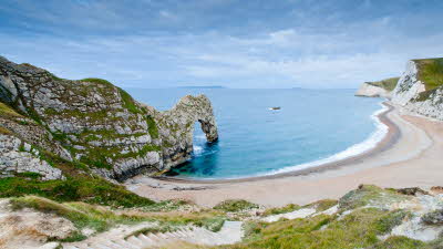 Durdle Door in Dorset with bright blue sky and sandy beach