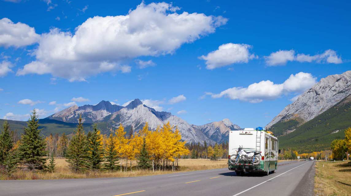 An RV cruises on the highway through the Canadian Rockies in Kananaskis, Alberta