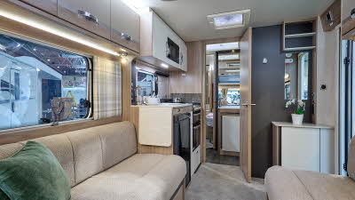 Swift Challenger Exclusive 560's interior has pale wooden furniture with beige upholstery.  The washroom is in the centre of the caravan with the bedroom at the rear.