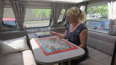 Writer Sammy Faircloth works on a jigsaw on a table inside her caravan