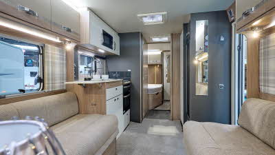 Swift Challenger Grande SE 670's interior has pale wooden furniture with beige upholstery.  The washroom is in the centre of the caravan with the bedroom at the rear.