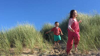 Happy children running down the dunes at Freshwater East