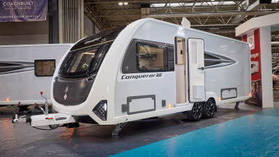 Swift Conqueror Grande 645 is white with black decals and a black front panel.  Its corner steadies are down and its entrance door is open.