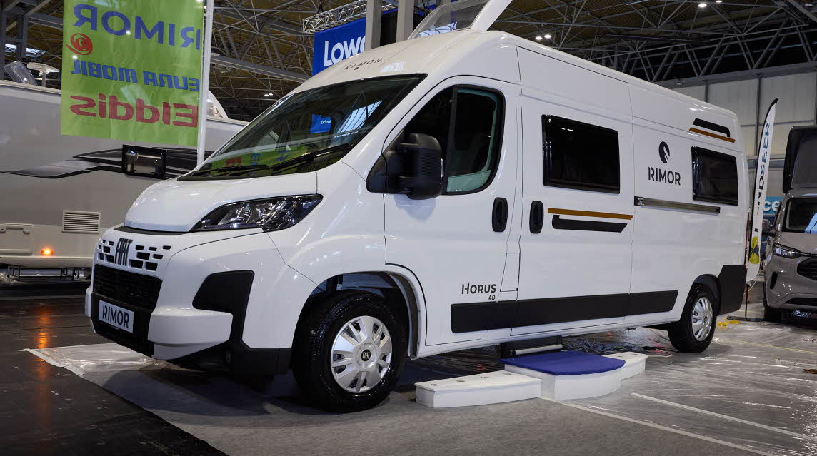 The Rimor Horus 40 is white with gold decals and black trim.  There are white steps by the closed sliding habitation door.  Its skylight is open.