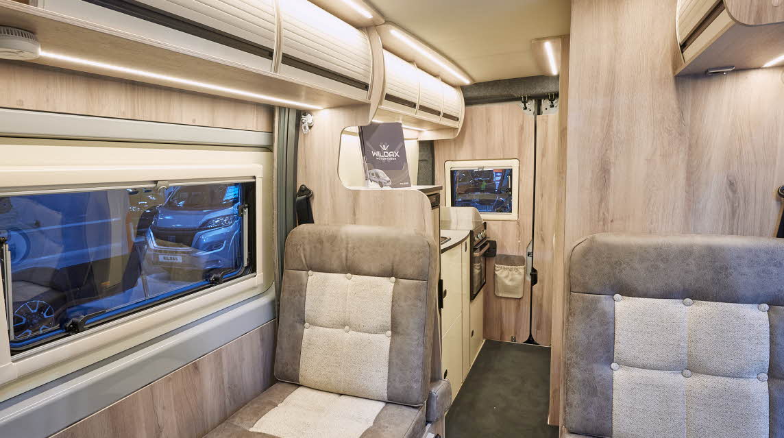 WildAx Pulsar MK2 has two tone beige and brown upholstery.  On the floor there is dark carpet.  The van has wooden panelling and there are cream coloured overhead lockers.