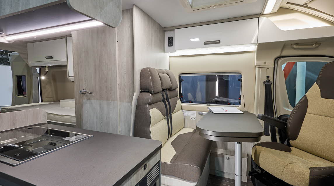 Roller Team Livingstone 6’s interior has brown and beige upholstery.  Its furniture is wooden.  At the rear there is a fixed bed.  The two rear seats have seatbelts.  The table is folded and can be extended.