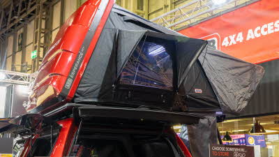 The ARB Esperance 2 has black canvas and a red hard shell roof.  Its windows are open.  It is displayed on a red car.