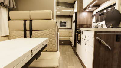 The Benimar Primero 282 has cream upholstery which is complemented with dark wooden furniture.  The kitchen is to the right and towards the rear, there is an end lounge.