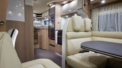 Carthago c-tourer T 148 LE H has cream leather upholstery, behind the rear travel seats Is the kitchen with a full oven and large fridge freezer.  At the rear of the vehicle is the fixed rear bed.