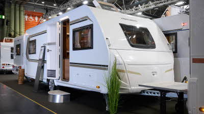 Weinsberg CaraOne 550 UK's exterior is white with brown and gold graphics.  The door is open and there is a step to enable easy access to the interior.