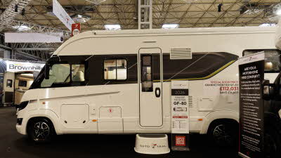 The Auto-Trail Grande Frontier GF-80 has a white and black exterior.  There is a step in front of the habitation door for easy access.  There is an information stand next to the door.