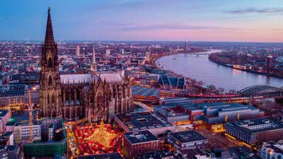 An elevated view of the city of Cologne with the Cathedral towering above a Christmas market