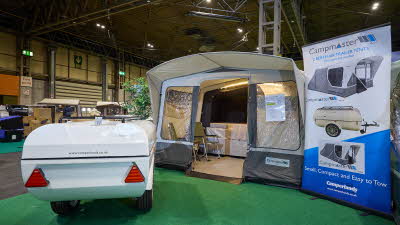Campmaster 1000 LX has cream and brown canvas.  The doors are open revealing the interior.  There are two camping chairs inside the main tent.  The folded unit, in white, is to the left.